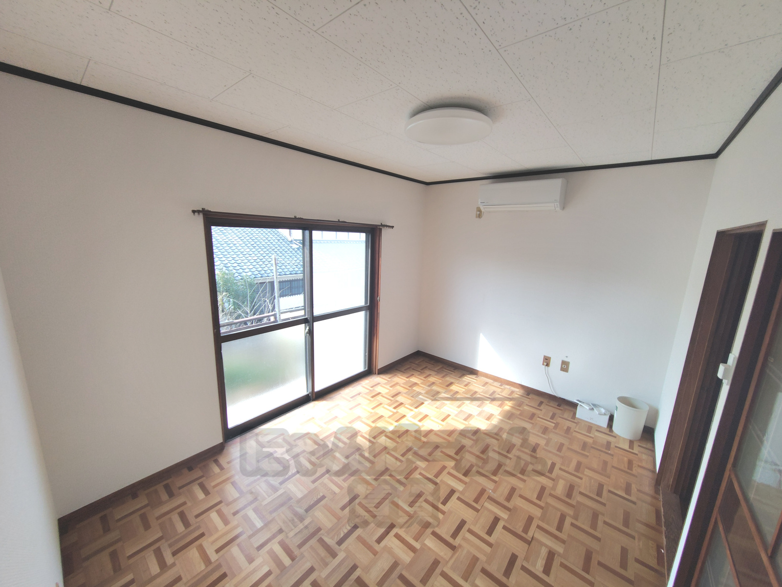 幾何学模様のフローリング床とエアコン完備の洋室