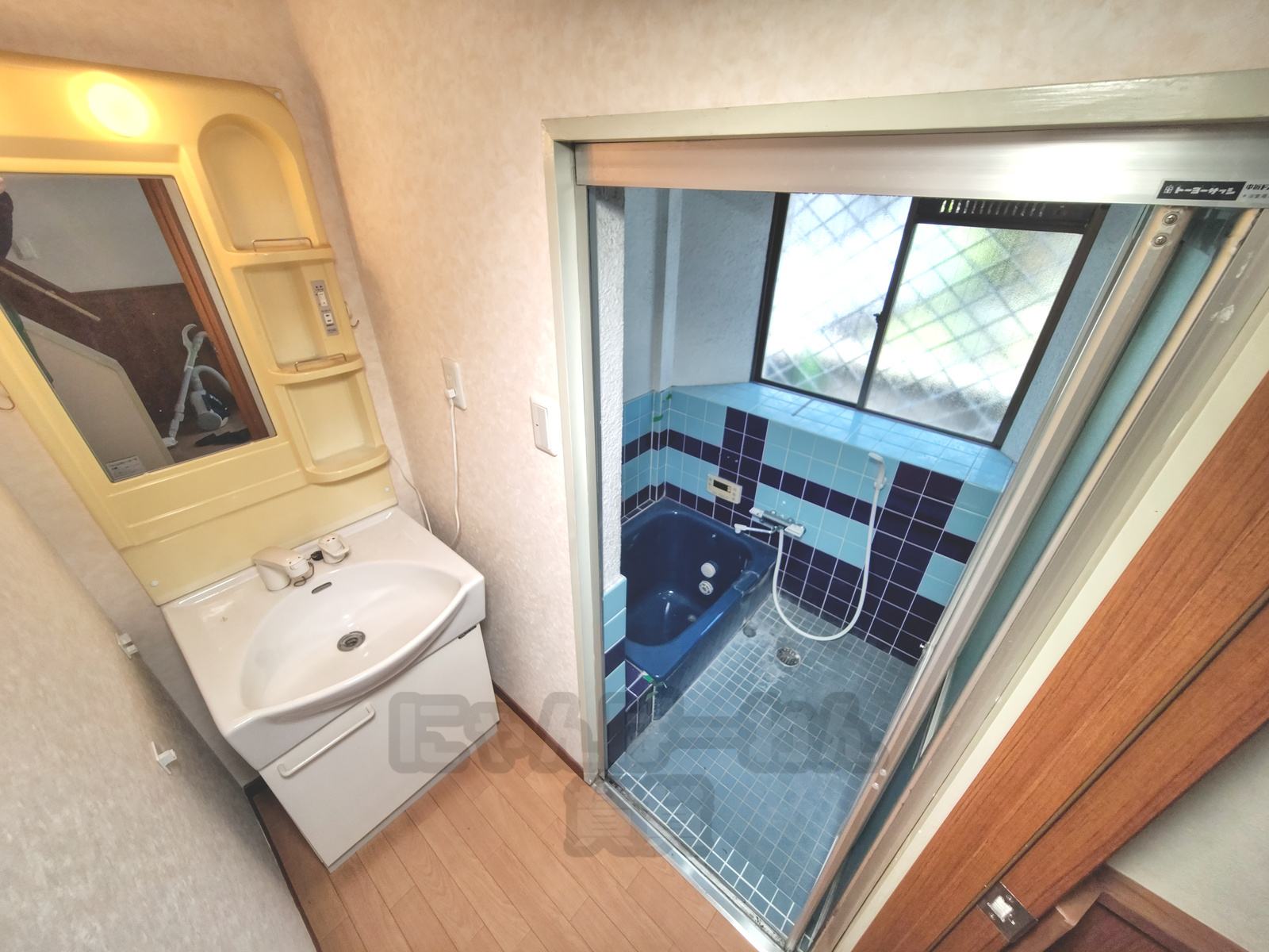 京都府宇治市小倉町久保のペット可賃貸物件の鏡付き独立洗面台と奥に見える青い浴室