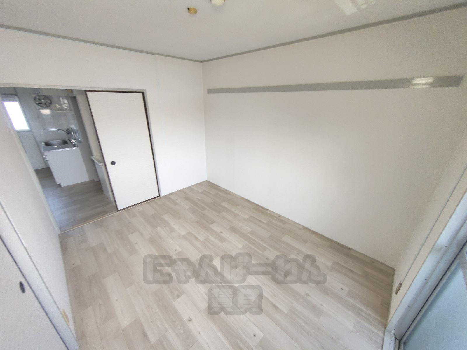 ピクチャーレールが壁に設置されたエバー・グリーン宇治弐番館305号室の木目調フローリング洋室