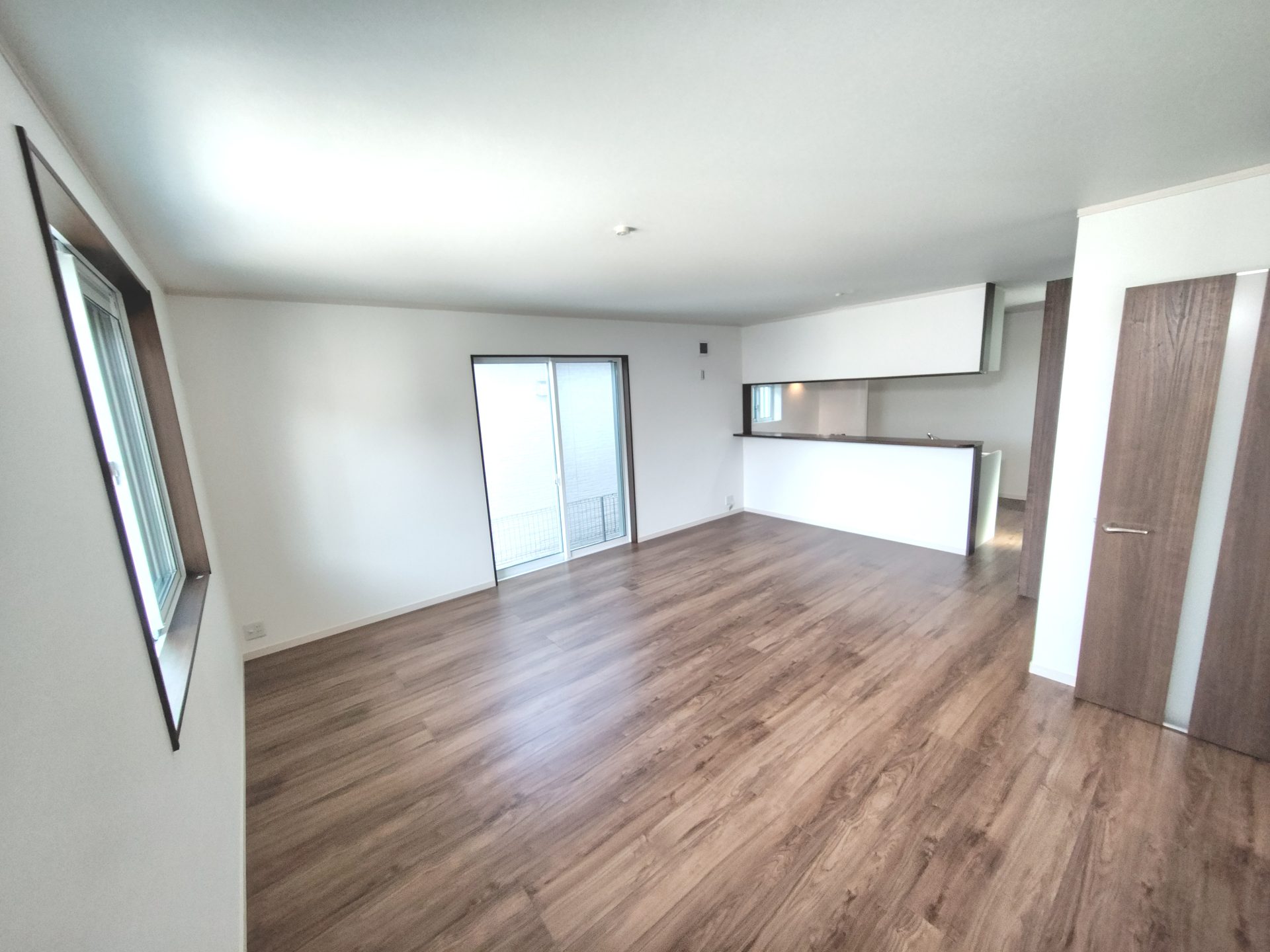 京都府京田辺市のペット可賃貸物件の木目調フローリングの居室と対面式カウンターキッチン