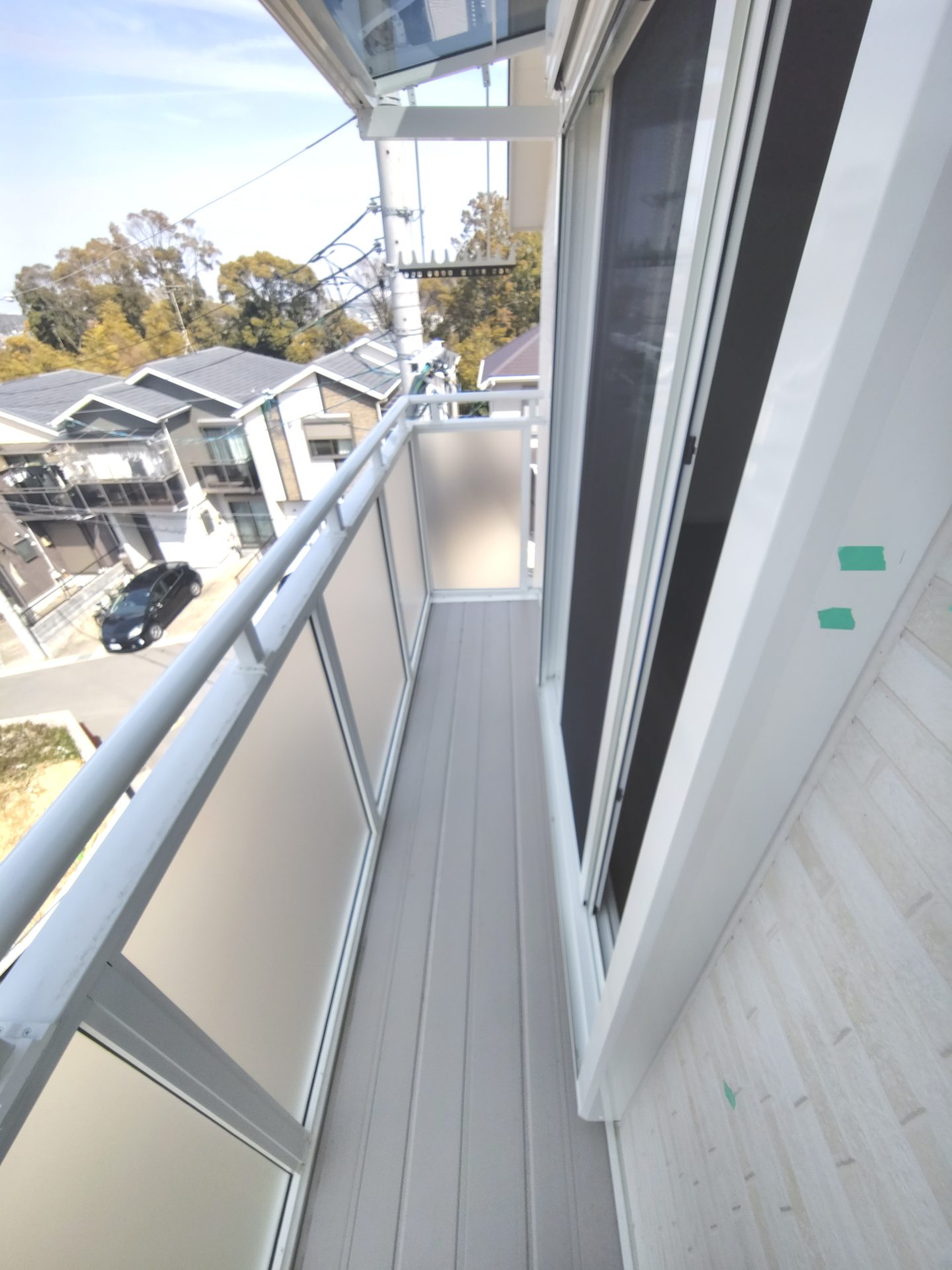 京都府京田辺市薪里ノ内の犬・猫と暮らせるペット可賃貸物件のバルコニー。半透明のパネル手すりと天井付けの物干し金物が設置されています。