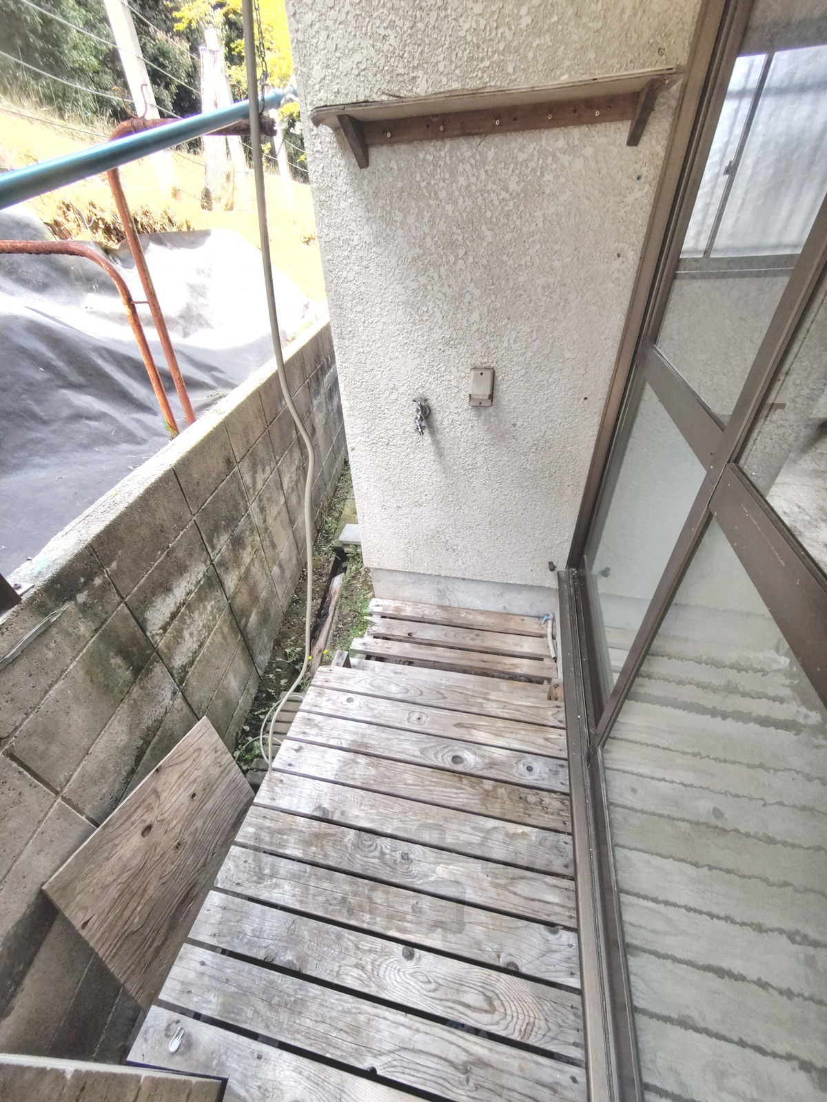 京都府宇治市木幡南山の犬猫飼育可賃貸物件の屋外木製デッキと外壁の水道