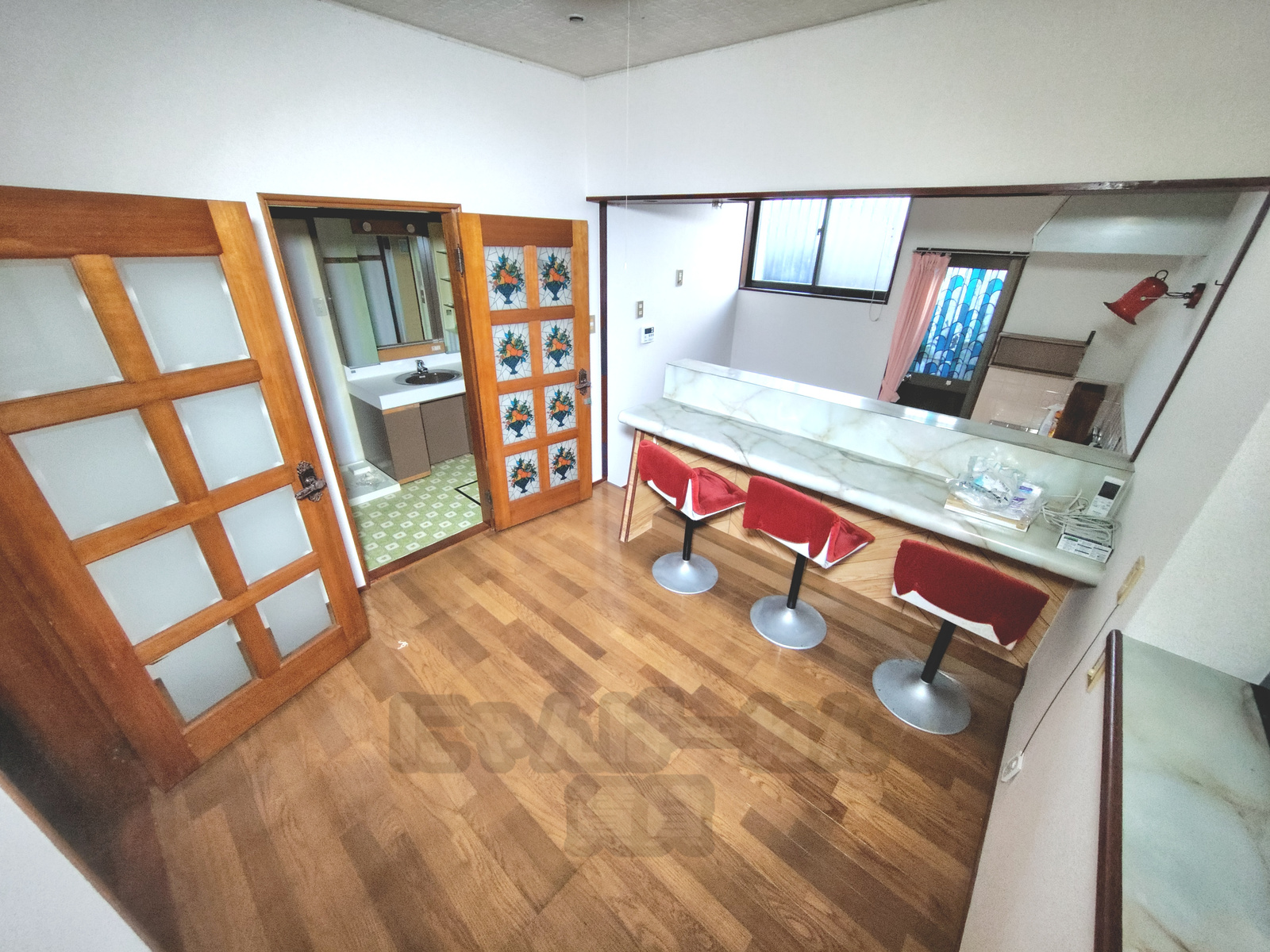 赤い椅子が並ぶカウンターと花柄の装飾ガラス扉があるダイニング