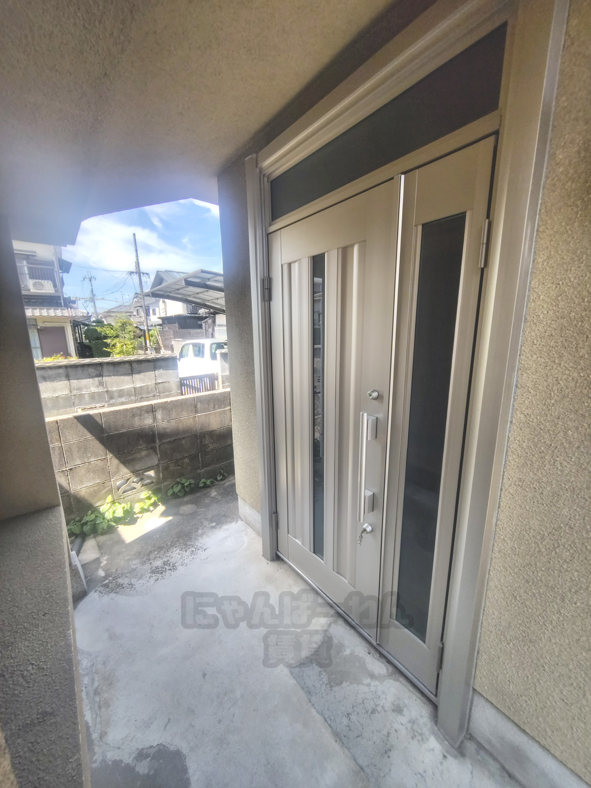京都府城陽市のペット可賃貸、シルバーのモダンな玄関ドアとコンクリート土間のポーチ。
