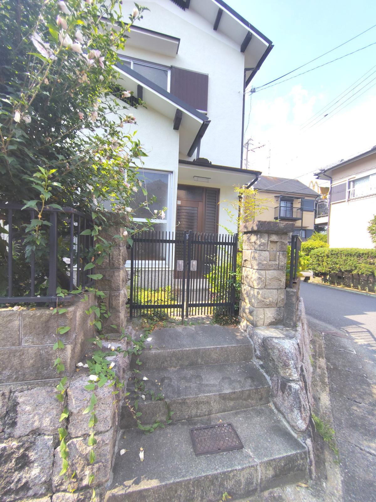 京都府宇治市木幡東中のペット可賃貸物件の門扉とアプローチ。石造りの階段の先に黒い門扉があり、奥に玄関ドアが見えます。